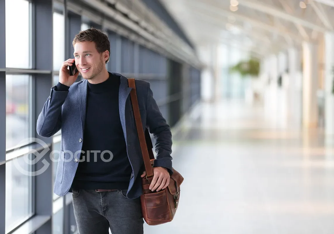 Man walking down a hallway and talking on a cell phone.