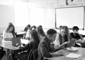 A picture of a wide angle view of high school students sitting at desks in classroom using laptops